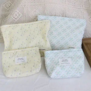 Detailed view of cute corduroy floral cosmetic bags with brand labels and soft texture.