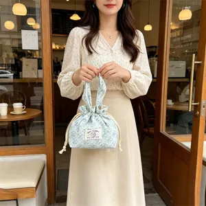 Detailed view of floral corduroy drawstring handbag with cute bow handles and front label.