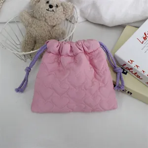 Gros plan du sac cordon matelassé rose, texture douce rembourrée avec cordons violets.
