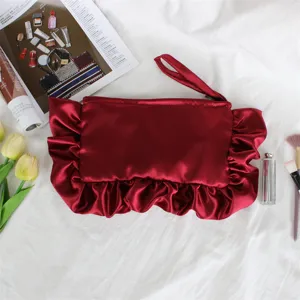Detalle del bolso de mano de satén rojo con volantes plisados y práctica correa de muñeca.