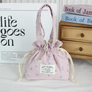 Vue détaillée de la pochette en toile rose avec cordon, joli imprimé et double poignées.