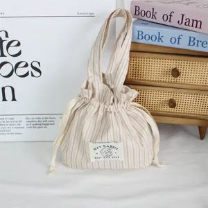 Vue détaillée du sac à main mignon en tissu rayé avec cordon de serrage et charmante étiquette.