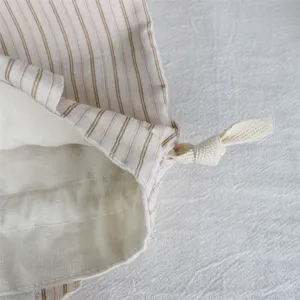 Gros-plan d'un sac de rangement en toile rayée avec cordon de serrage et doublure intérieure.