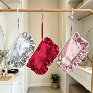 Detalle de bolso de mano de satén con volantes, elegante neceser plateado rojo rosa.