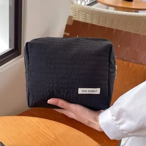 Schwarze, geknitterte Kosmetiktasche mit Reißverschluss und Label, tragbarer Reise-Organizer.