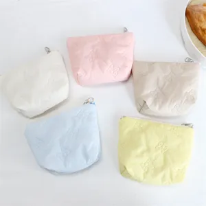 Close-up of cute quilted cartoon cosmetic bags with zipper, pastel colors and soft texture.
