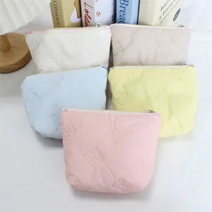 Close-up of cute quilted cosmetic pouches in pastel colors with sweet bow embossing details.