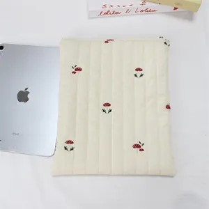 Quilted tablet sleeve detail, beige pouch with cute mushroom embroidery, soft inner lining.