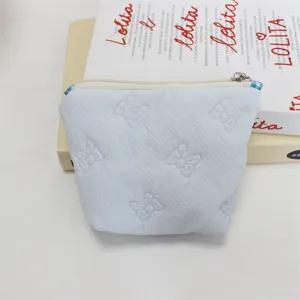 Light blue quilted makeup pouch detail, cute embossed bow design with secure zipper closure.