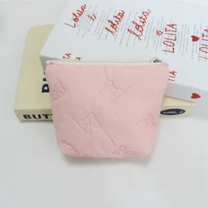 Close-up of pink quilted cosmetic pouch with cute embossed bows and secure zipper closure.