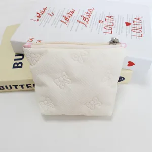 Detail view of a cute quilted bow coin purse in cream, perfect for portable storage.