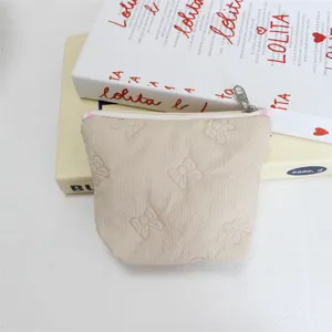 Close-up view of the beige quilted mini pouch with cute embossed bows and zipper closure.