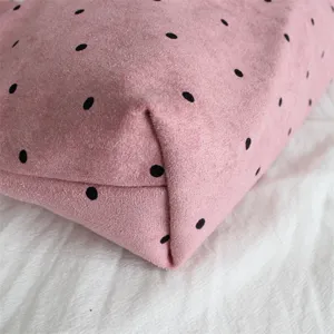 Detail view of pink suede polka dot bag showing soft fabric texture and stitching.