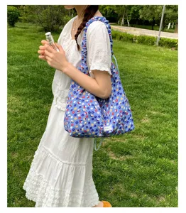 Outdoor detail shot of blue floral shoulder bag with ruffled straps, casual chic daily wear.