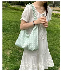Light green polka dot shoulder bag for women, casual hobo handbag with ruffled strap.