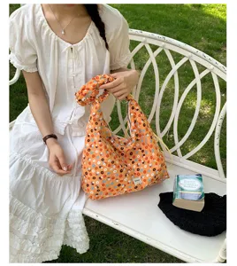 Detailed view of the orange floral shoulder bag with matching scrunchie and adjustable strap.