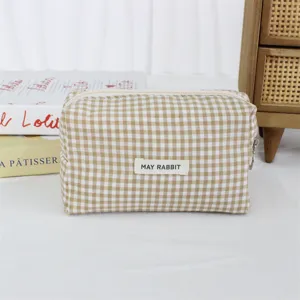 Detailaufnahme der beigen Karos Kosmetiktasche mit Stofftextur, Reißverschluss und Etikett.