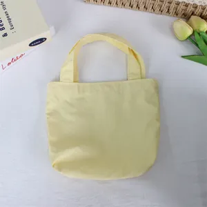 Solid yellow nylon mini tote bag, lightweight casual handbag and practical lunch bag detail.