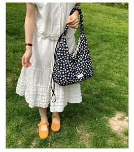 Detailed view of the floral print shoulder bag worn outdoors on model, casual hobo style.