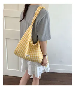 Detailed view of yellow plaid shoulder bag with stylish scrunchie strap for women.