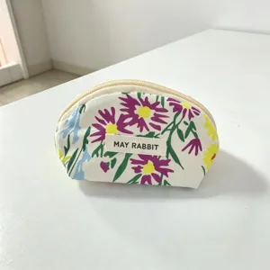 Close-up detail of the floral canvas cosmetic pouch showing delicate print and sturdy zipper.