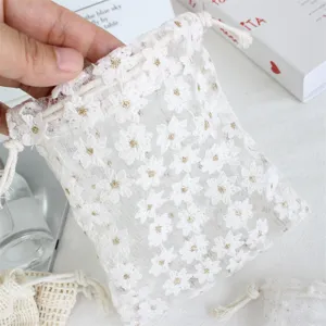 White mesh daisy embroidery drawstring pouch detail, delicate floral gift jewelry storage bag.