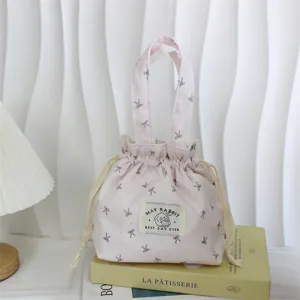 Pink corduroy drawstring handbag detail shot, cute bow print aesthetic bento bag and storage pouch.