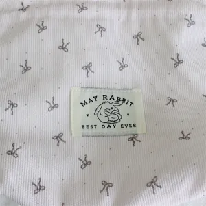 Corduroy handbag detail view, cute bow print and rabbit logo label, portable storage bag.