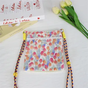 Detailansicht der Blumen-Canvas-Umhängetasche mit verstellbarem, buntem Riemen und Spitze.