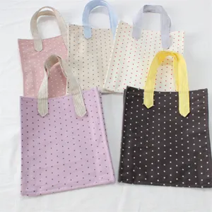 Dettagli di piccole borse tote in tela con stampa di stelle e manici a righe in vari colori.