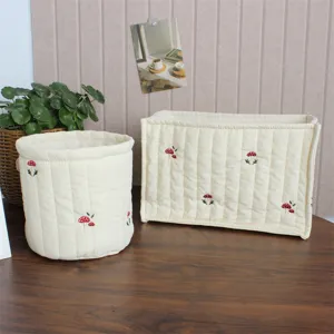 Detailed view of cute quilted fabric storage baskets with embroidered mushroom patterns.