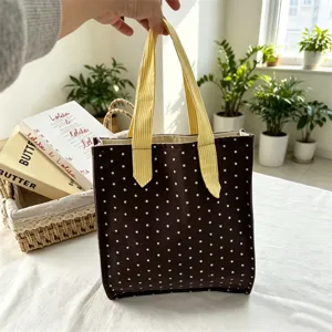Primo piano dettagliato della borsa in tela marrone con stelle bianche e manici a righe.