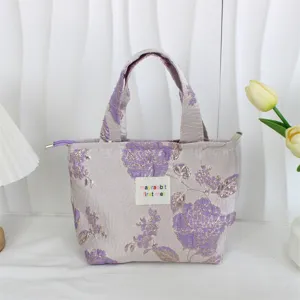 Vintage floral jacquard tote bag detail, elegant purple fabric with texture, close-up view.