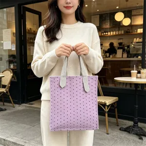 Primo piano della borsa tote in tela viola con stampa di stelle e manici a righe, stile casual.