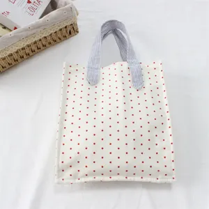 Vista di dettaglio di una borsa tote in tela con stampa di stelle rosse e manici blu.