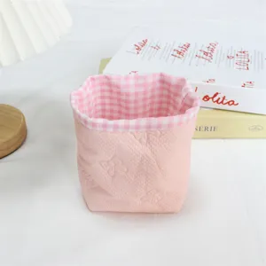 Panier de rangement de bureau en tissu rose avec doublure a carreaux et noeud en relief.