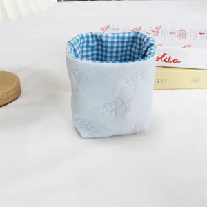 Vue détaillée du panier en tissu à carreaux bleus, joli motif de nœud pour le bureau.