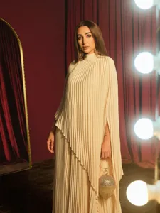 Detailed view of the elegant beige pleated long sleeve dress featuring an asymmetric hem.