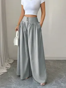 Detailed view of high waist wide leg trousers with three buttons and draping fabric design.