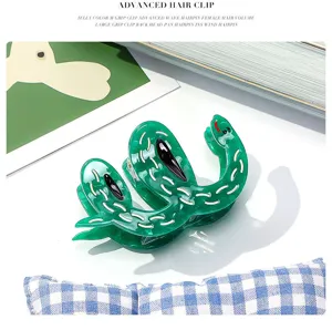 Detail view of the green snake acetate hair claw clip featuring stylish wavy pattern.