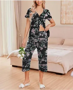 Detailed view of women floral print short sleeve pajama top and cropped pants set in bedroom.