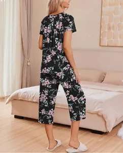 Back view detail of floral short sleeve pajama top and capri pants set in cozy bedroom scene.