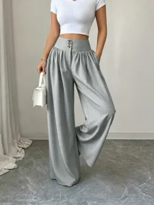 Detailed view of high-waisted wide-leg trousers with three buttons and draping fabric.