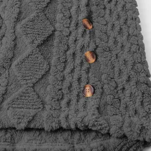 Dunkelgrauer Fleece-Mantel Detail, gemütliche Textur mit braunen Knöpfen. Perfekte Winterkleidung Nahaufnahme.