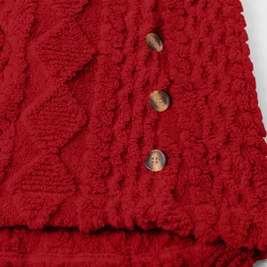 Nahaufnahme von rotem Plüschfleece Stoff mit Knöpfen, weiches Wintermantel Detail.