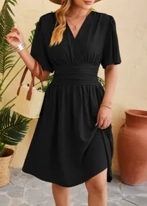 Detail view of black v-neck dress, showcasing cinched waist and flare sleeves in a lifestyle setting.