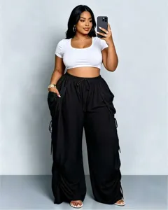 Completo casual taglie forti donna con crop top bianco e pantaloni larghi neri.