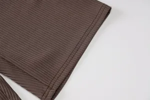 Close-up detail of brown ribbed knit fabric showing fine texture and neat stitching seams.