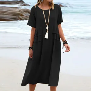 Detail view of the loose black midi dress worn on beach, showing short sleeves and hemline.
