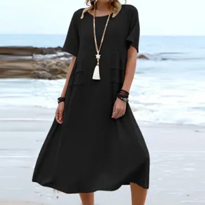 Detail view of a casual black short sleeve midi dress worn on a scenic beach backdrop.